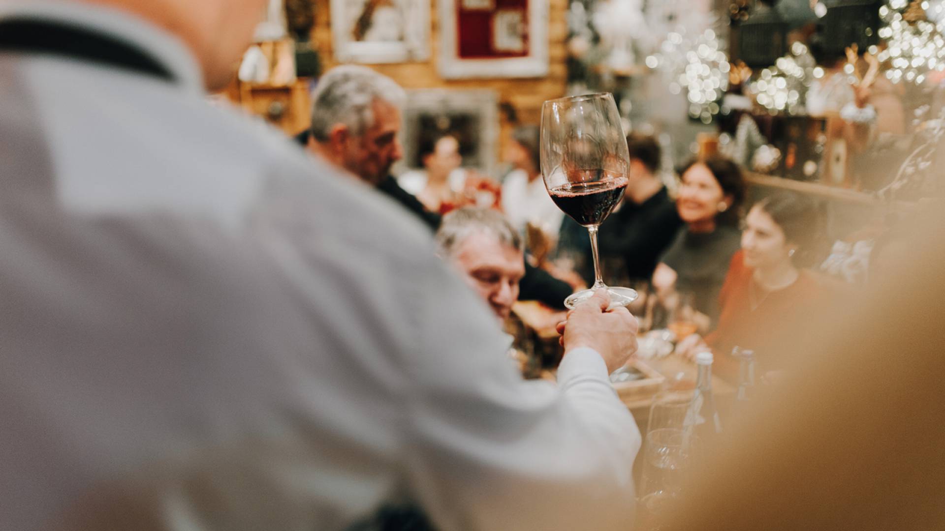 Gastgeber hebt das Glas Wein um anzustoßen - Tre.CULINARIA